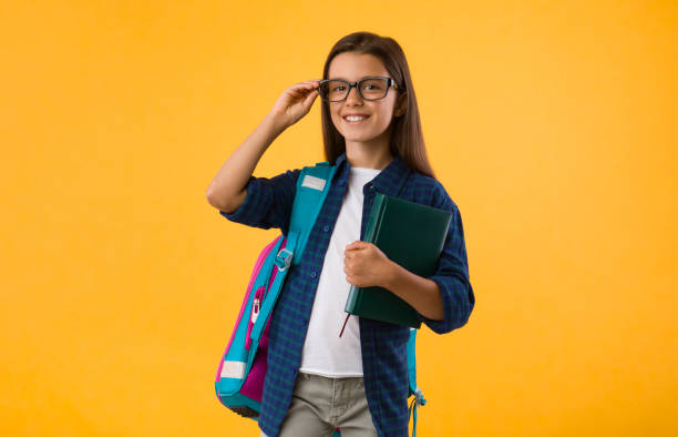 istock Girl with glasses and book standing in studio 1269064000
