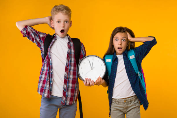 surprised shocked little boy and girl holding clock at studio - clock clock face blank isolated imagens e fotografias de stock