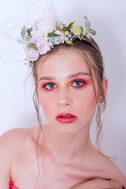 Extra close up portrait of a beauty young girl with nude fashion bright make-up Extra close up portrait of a beauty young girl with nude fashion bright make-up, a hairstyle on head, a hoop made of fresh flowers: peons, field flowers, eucalyptus, ranunculus. Clean skin. Bridesmaid hoops wedding stock pictures, royalty-free photos & images