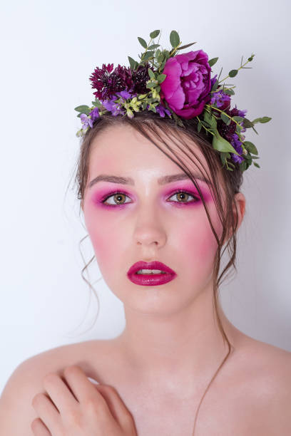 Close up beauty portrait of a girl with bright lilac professional make-up Close up beauty portrait of a girl with bright lilac professional make-up, lipstick, shadows, a hairstyle on her head and a hoop made of fresh flowers: peonies, field flowers, eucalyptus. Bridesmaid hoops wedding stock pictures, royalty-free photos & images
