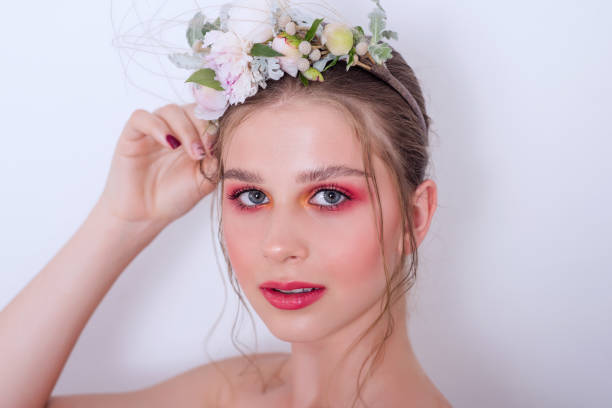 Extra close up portrait of a beauty young girl with nude fashion bright make-up Extra close up portrait of a beauty young girl with nude fashion bright make-up, a hairstyle on head, a hoop made of fresh flowers: peons, field flowers, eucalyptus, ranunculus. Clean skin. Bridesmaid hoops wedding stock pictures, royalty-free photos & images