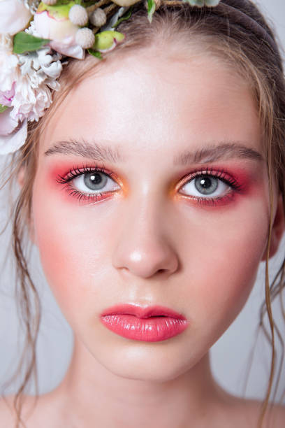 Extra close up portrait of a beauty young girl with nude fashion bright make-up Extra close up portrait of a beauty young girl with nude fashion bright make-up, a hairstyle on head, a hoop made of fresh flowers: peons, field flowers, eucalyptus, ranunculus. Clean skin. Bridesmaid hoops wedding stock pictures, royalty-free photos & images