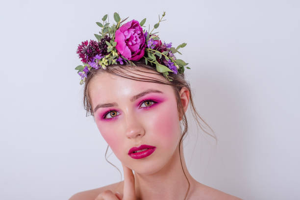 Close up beauty portrait of a girl with bright lilac professional make-up Close up beauty portrait of a girl with bright lilac professional make-up, lipstick, shadows, a hairstyle on her head and a hoop made of fresh flowers: peonies, field flowers, eucalyptus. Bridesmaid hoops wedding stock pictures, royalty-free photos & images