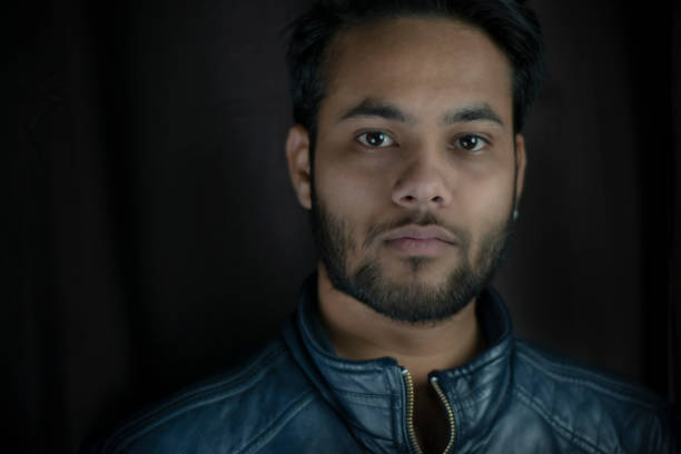 istock low key portrait of young man looking at camera with blank expression. 1269092245