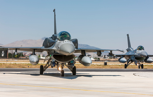 Bagotville, Quebec – January 17, 2024: A Royal Canadian Air Force FA-18 from RCAF Wing 3 is arriving at the Bagotville, Quebec, air base.  The landing FA-18 is creating some air flow lines as it banks for final approach to the runway in front of a rising moon.