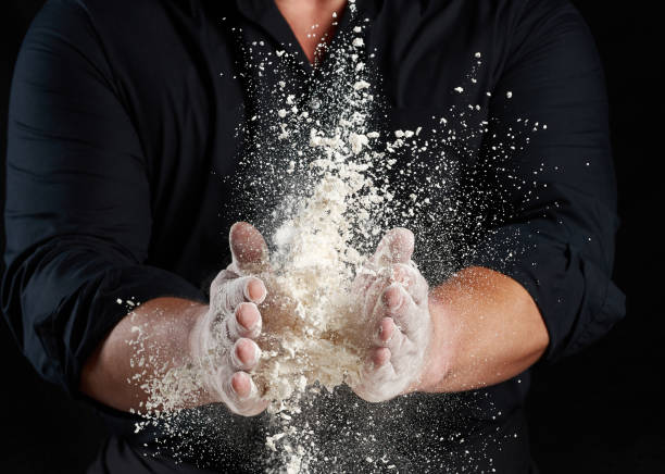 istock chef in black uniform sprinkles white wheat flour in different directions, product scatters dust 1269095364