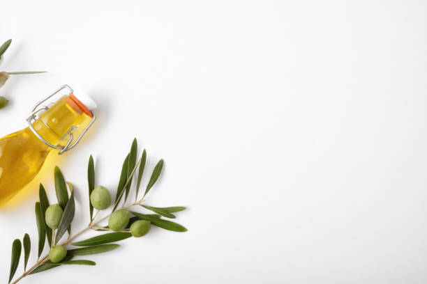 istock Bottle with oil and olive twig on white table top 1269098575