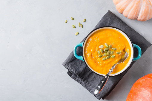 Autumn pumpkin soup on grey background. View from above and space for text.