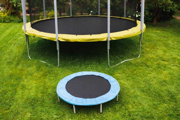istock small trampoline near big one with round mat, size comparison, green lawn background 1269098922