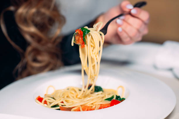 istock Young beautiful woman eating pasta in a restaurant. 1269099088