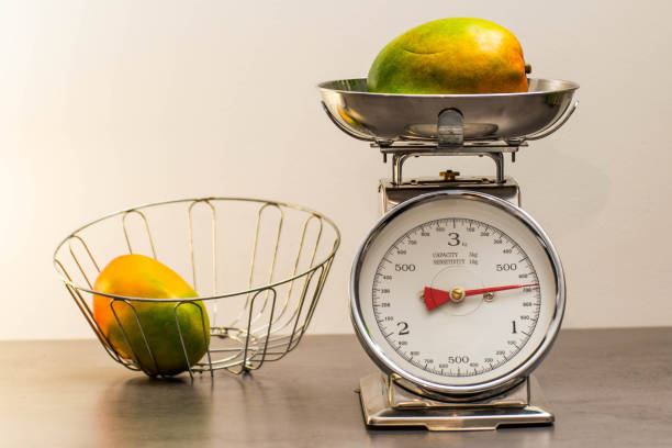 Vintage kitchen scale with mangos A silver vintage kitchen scale. Retro style. With two mangos. vintage kitchen scale with fruit stock pictures, royalty-free photos & images