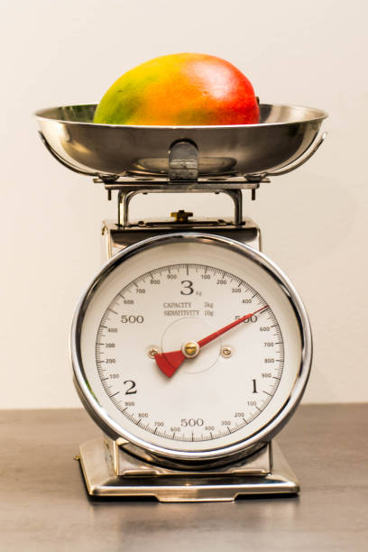 Vintage kitchen scale with a mango A silver vintage kitchen scale. Retro style. With a mango. vintage kitchen scale with fruit stock pictures, royalty-free photos & images