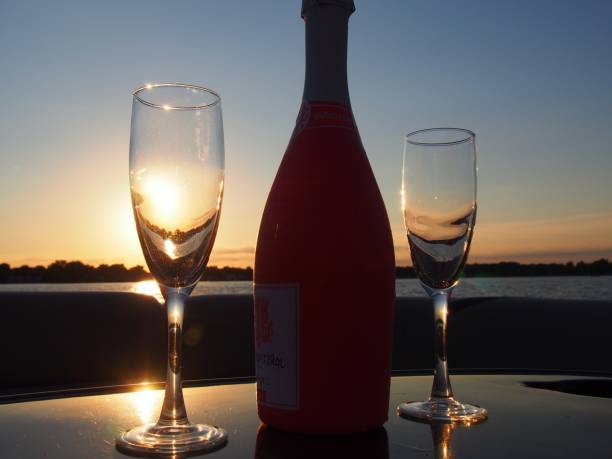 Champagne Bottle with Two Champagne Glasses on a Boat at Sunset It's sunset on a boat with two champagne glasses and a bottle of Rose Wine drinks on the deck stock pictures, royalty-free photos & images