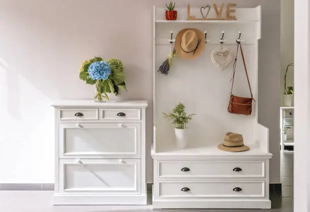 Home interior. White wooden furniture at entryway. Small foyer organisation decision.