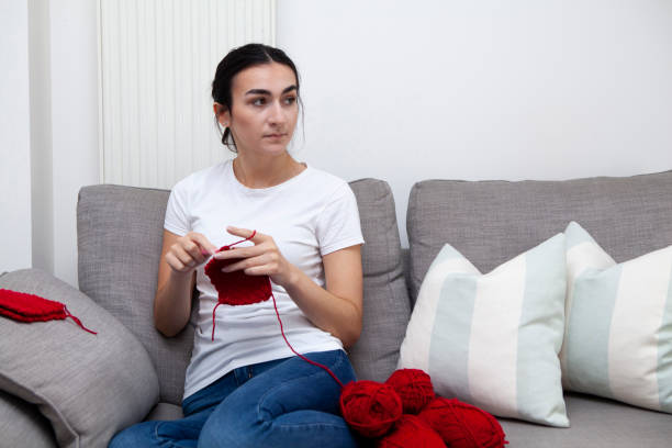 istock Young woman doing crochet on sofa at home and looking to the side with copy space 1269115281