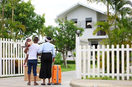 African American family is moving in to a new house with father holding baby with suitcase and baggage for housing and relocation concept