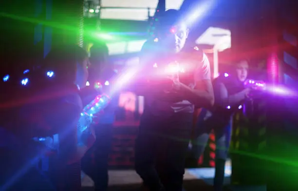 Photo of Emotional guy playing laser tag in colorful beams