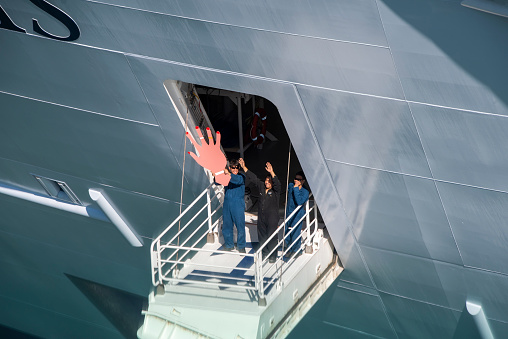 Barcelona, Spain - June 7, 2016:  Friendly crew members waving from Royal Caribbean's newest ship, the Harmony of the Seas, in port in Barcelona.