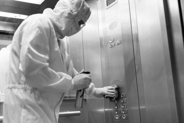 istock Coronavirus infection. Paramedic in protective mask and costume disinfecting an elevator with sprayer, 1269120389