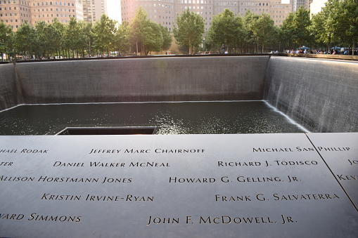 New York, USA - August 16, 2015: Names of the victims of attacks inscribed on the parapets surrounding the waterfalls of National September 11 Memorial.