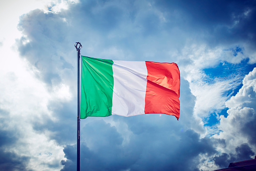 Italian three colors flag of Italy on the blue sky background