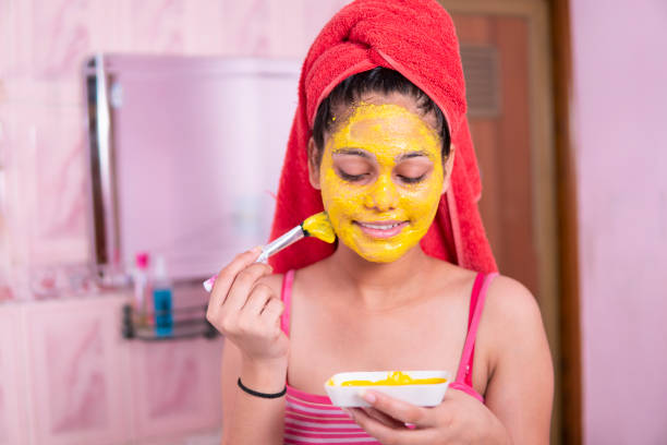 istock Beautiful girl applying yellow turmeric face pack on face. 1269124103