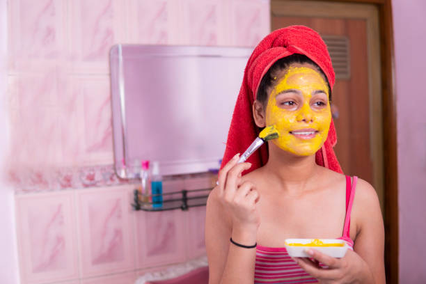 istock Beautiful girl applying yellow turmeric face pack on face. 1269124119