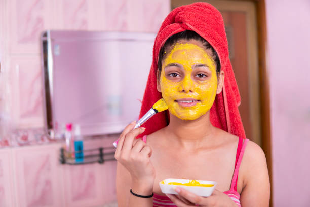 istock Beautiful girl applying yellow turmeric face pack on face. 1269124120