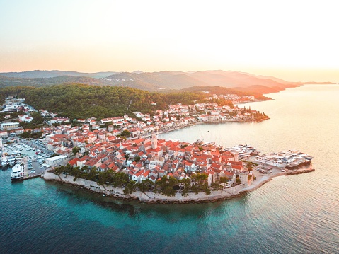 Aerial view of an old sea town Korcula in Croatia, surrounded by clear blue waters and marina with ancored sailboats and yachts.