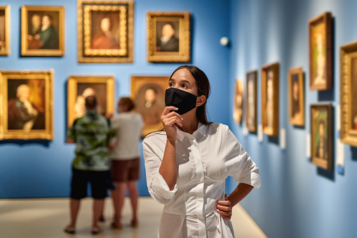 woman visitor wearing an antivirus mask in the historical museum looking at pictures