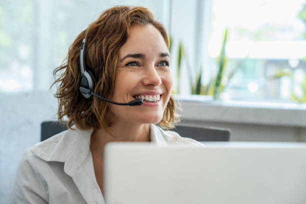 Customer service representative wearing headset in the office Close-up of smiling mature female customer service representative wearing headset in office headset stock pictures, royalty-free photos & images