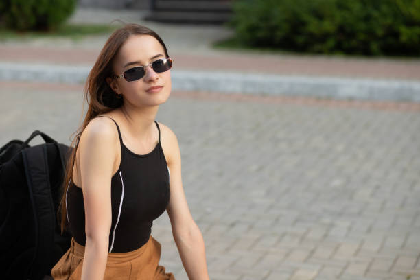 istock A student girl with a backpack is sitting on a bench in a city Park, smiling 1269128280