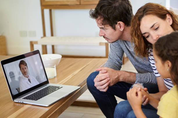Family having video call with doctor on laptop Parents consulting their daughter's illness with doctor on video call couples online counseling stock pictures, royalty-free photos & images