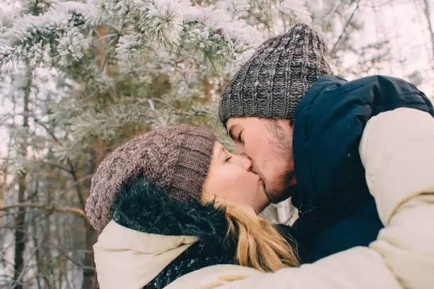 Photo of Kissing couple in winter forest.