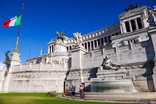 Rome, Italy, August 04 -- Some tourists take photo at the Altare della Patria or Vittoriano, the Italian national monument built in the historic center of Rome on the northern slope of the Campidoglio (the Roman Capitol Hill) and Piazza Venezia between 1885 and 1935 in honor of the first King of Italy, Vittorio Emanuele II. Inside there is the Altare della Patria and the Monument to the Unknown Soldier, the National Memorial Monument dedicated to all Italian soldiers who died in wars. The Altare della Patria is the setting for all the official Italian celebrations, in particular the National Day of the Republic of 2 June and the Liberation Day on April 25th. Image in High Definition format.