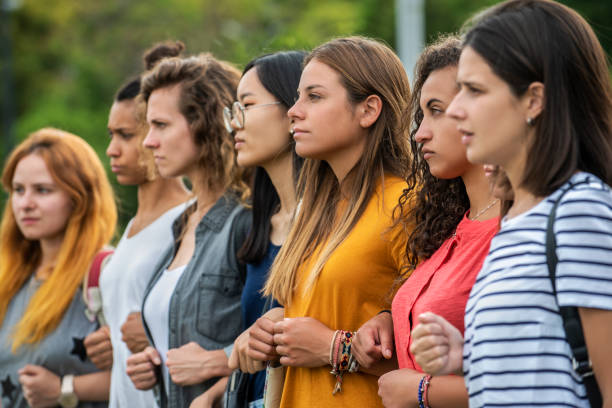 Women standing together Group of young female protestors with arms in arms and clenching fist while standing together outdoors womens rights photos stock pictures, royalty-free photos & images