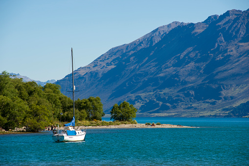 Glenorchy, New Zealand - December 25, 2018. A small boat on Lake Wakatipu with people on beach at Glenorchy, South Island, New Zealand