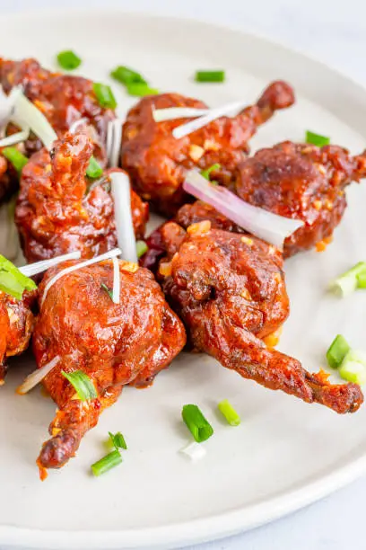 Popular Indo-Chinese Chicken Appetizer Made of Chicken Winglets on a White Plate