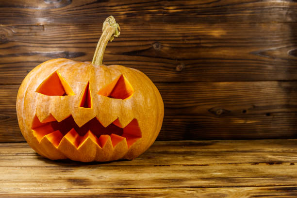 istock Spooky Halloween pumpkin jack-o-lantern on a wooden background 1269139982