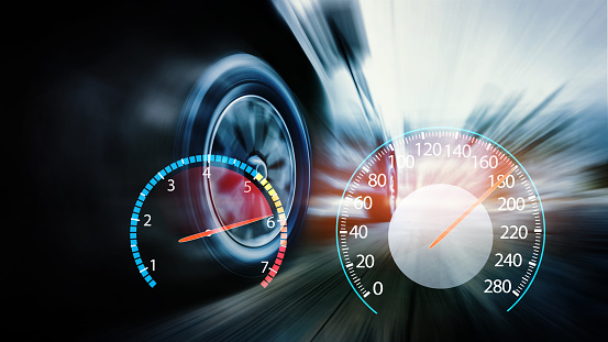 Speeding car with speedometer. Low angle side view of car driving fast on motion blur