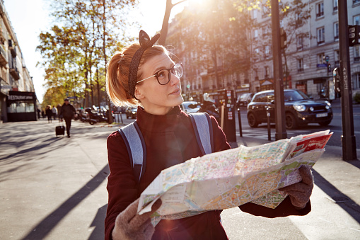 Woman tourist using city map in Paris streets, France.