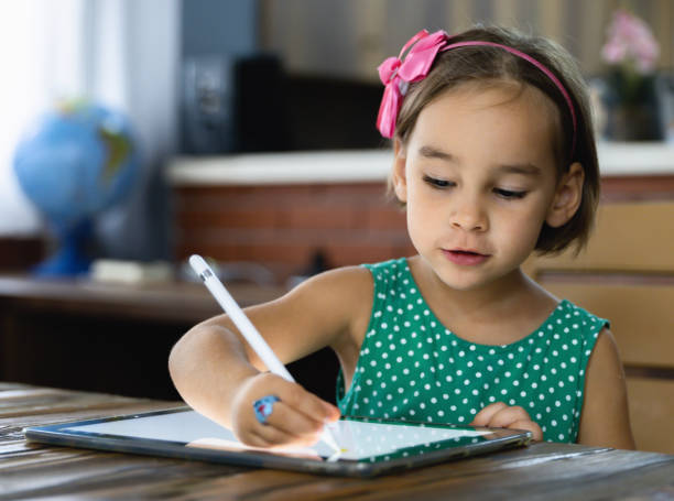 istock Child Girl Is Drawing Picture On Digital Tablet Using Stylus Pen 1269141787