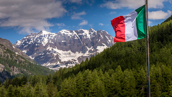 Italian flag waving in Alpine landscape, majestic Dolomites alps – Gran Paradiso, Italy