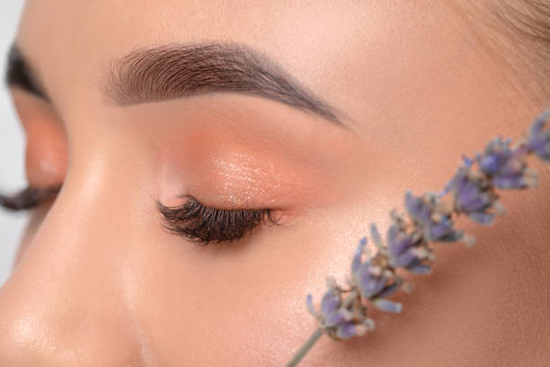 Eyes and eyebrows close-up.Portrait of a beautiful teenage girl with beautiful makeup, extended long eyelashes and healthy clean skin.Near the eyes is branch of lavender.Makeup and cosmetology concept Eyes and eyebrows close-up.Portrait of a beautiful teenage girl with beautiful makeup, extended long eyelashes and healthy clean skin.Near the eyes is branch of lavender.Makeup and cosmetology concept hair threading stock pictures, royalty-free photos & images