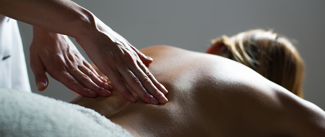 Beautiful young pregnant woman enjoying and relaxing during special massage treatment for maintaining healthy pregnancy.