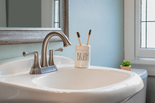 istock Two bamboo toothbrushes in a ceramic container on the bathroom sink 1269151261