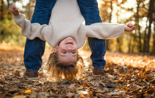 秋の森で小さな娘を逆さまに抱いている認識できない父親。 - middle human age leaf tree ストックフォトと画像