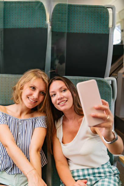 istock Two smiling girlfriends in train taking selfies 1269153506