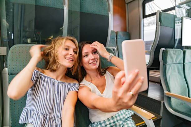 istock Two smiling girlfriends in train taking selfies 1269153512