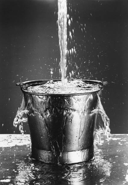 Black and white photo of Water pouring into a bucket stock photo